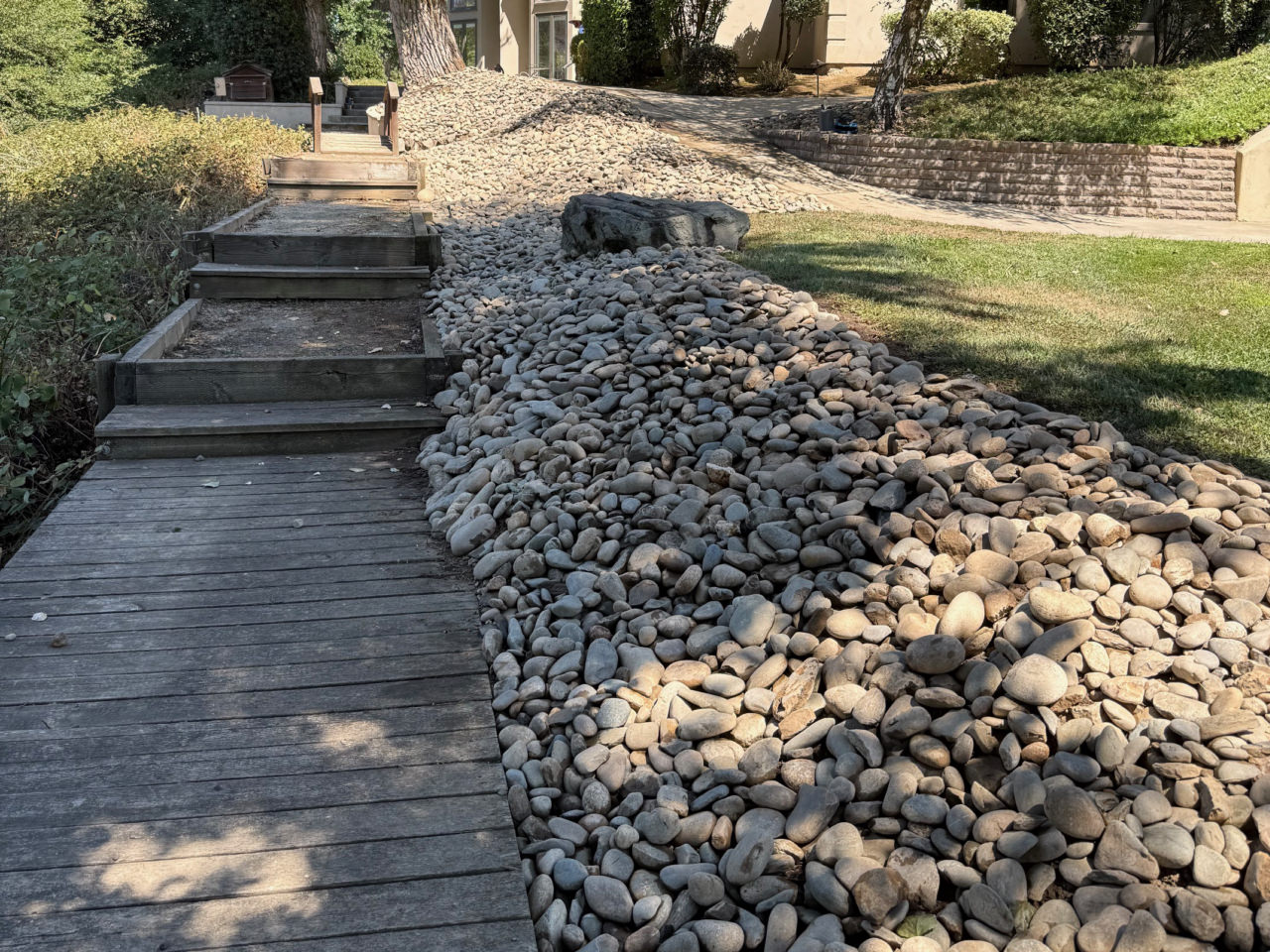 large stones creating a barrier between a lawn and walkway