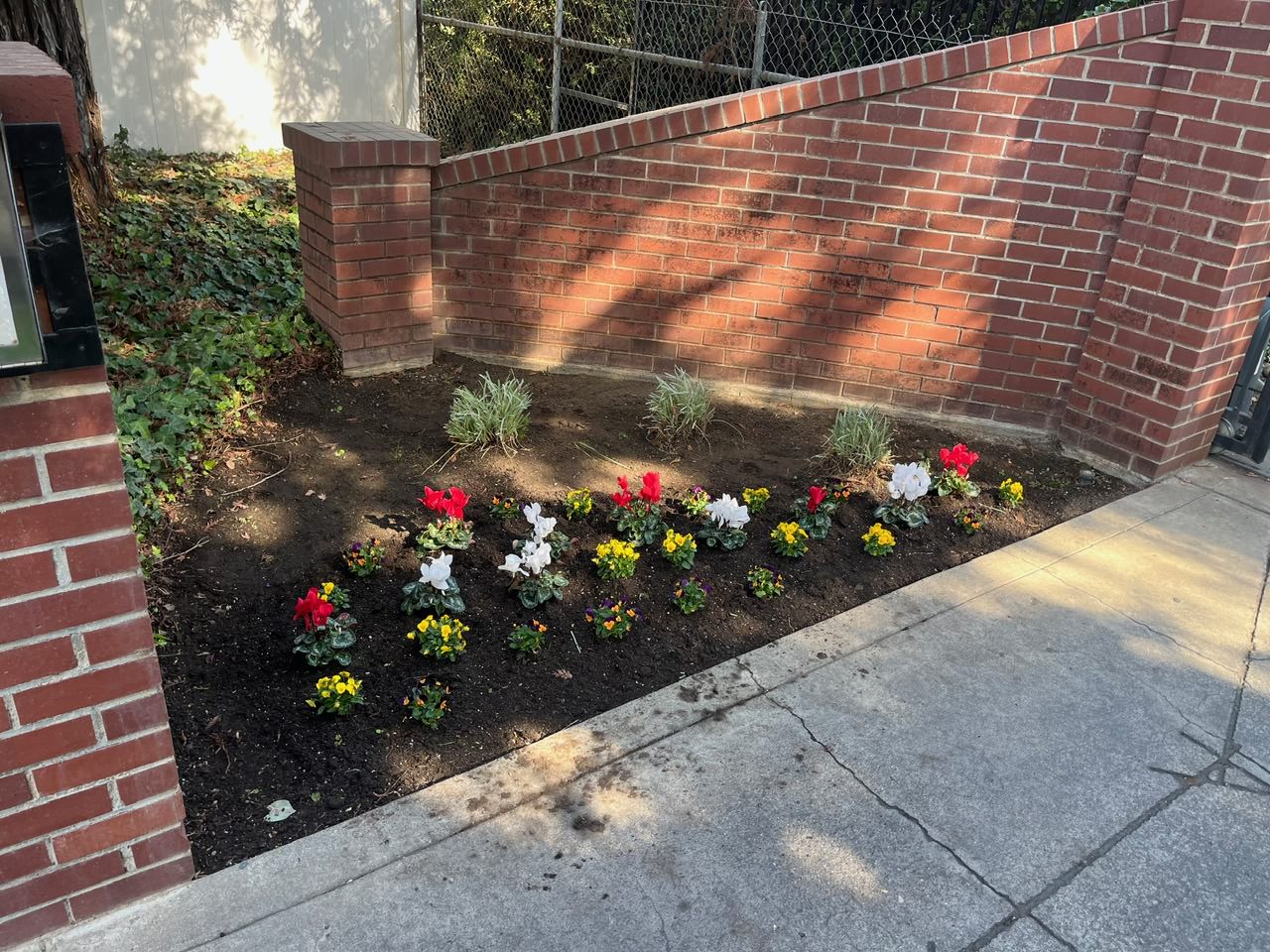 freshly planted flowers next to a gated community entrance