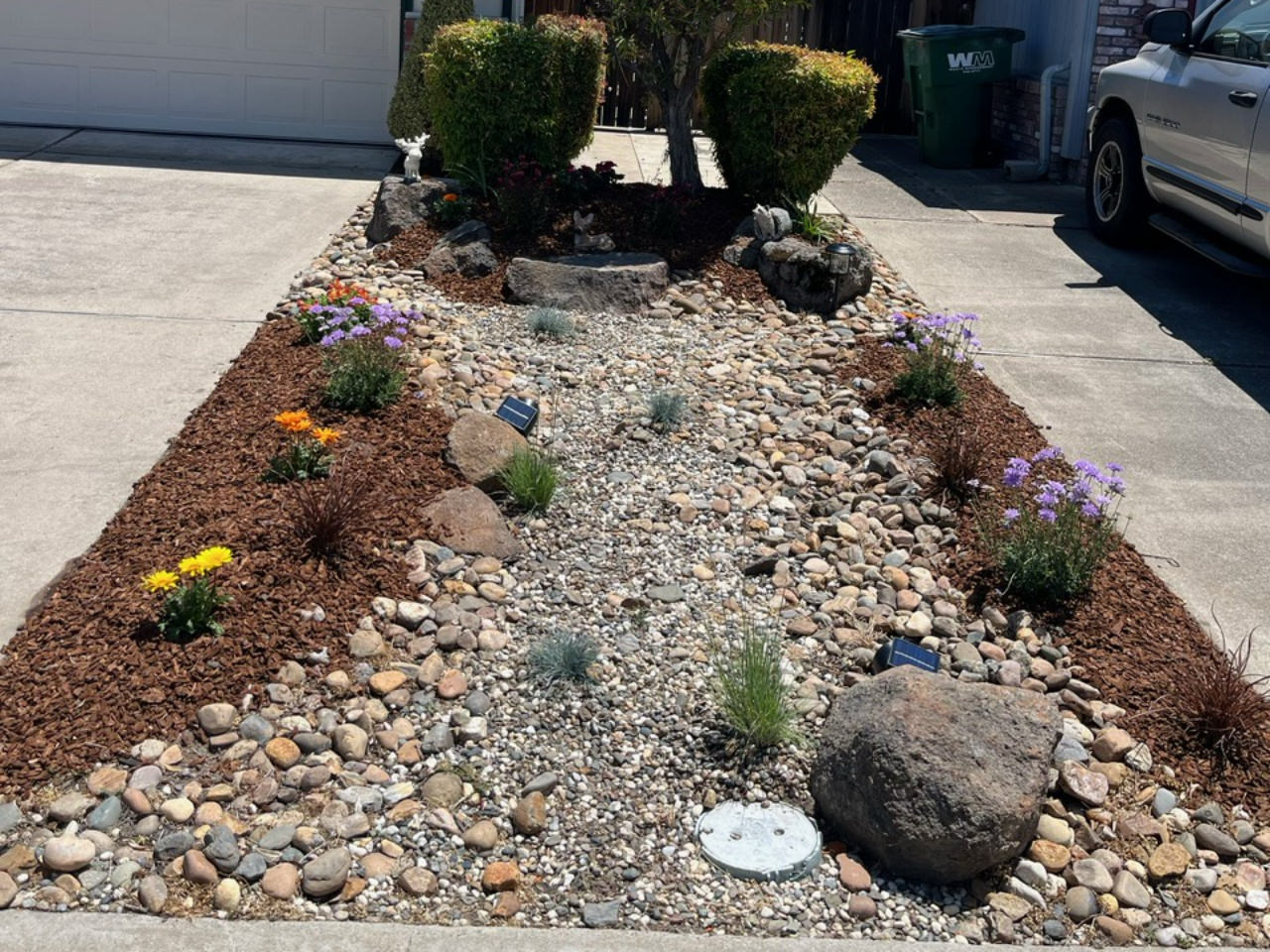 low maintenance designed landscape with rocks and bark for between driveways