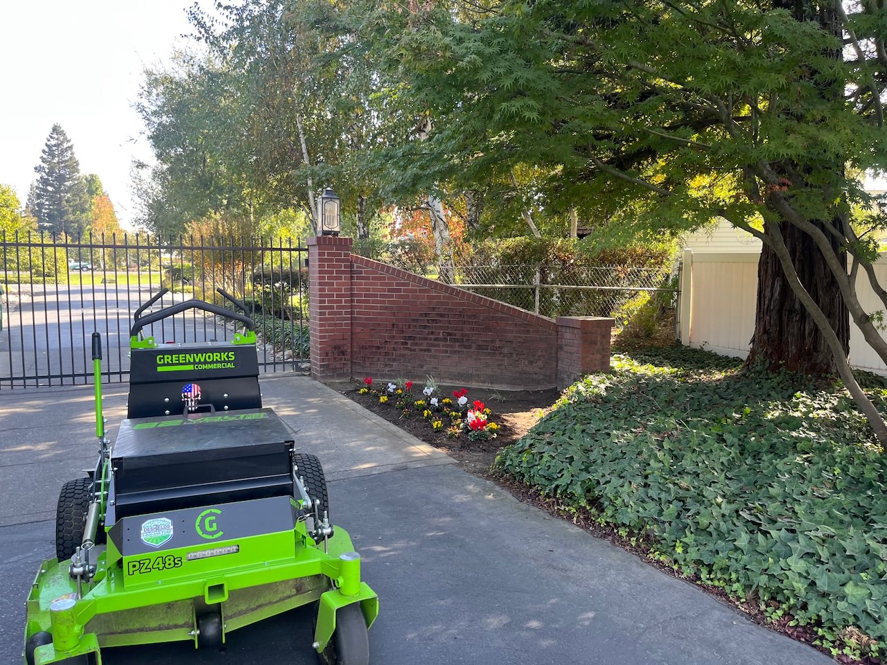 commercial lawn mower next to newly planted flowers and trimmed hedges